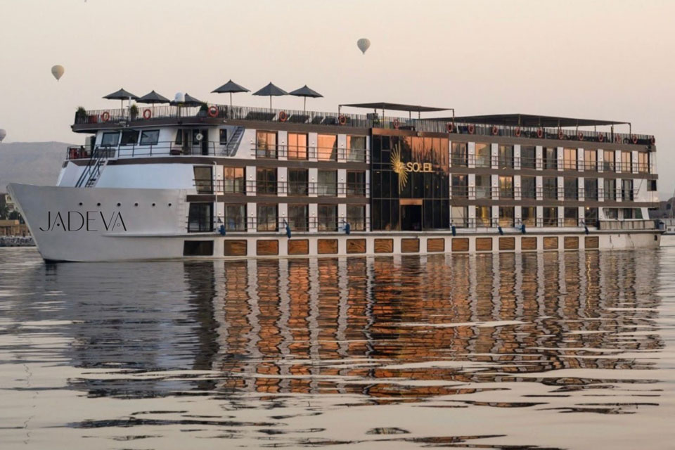 Luxury river yacht JADEVA sails the Nile at sunset, reflecting its golden light on calm waters during a transformational leadership expedition.